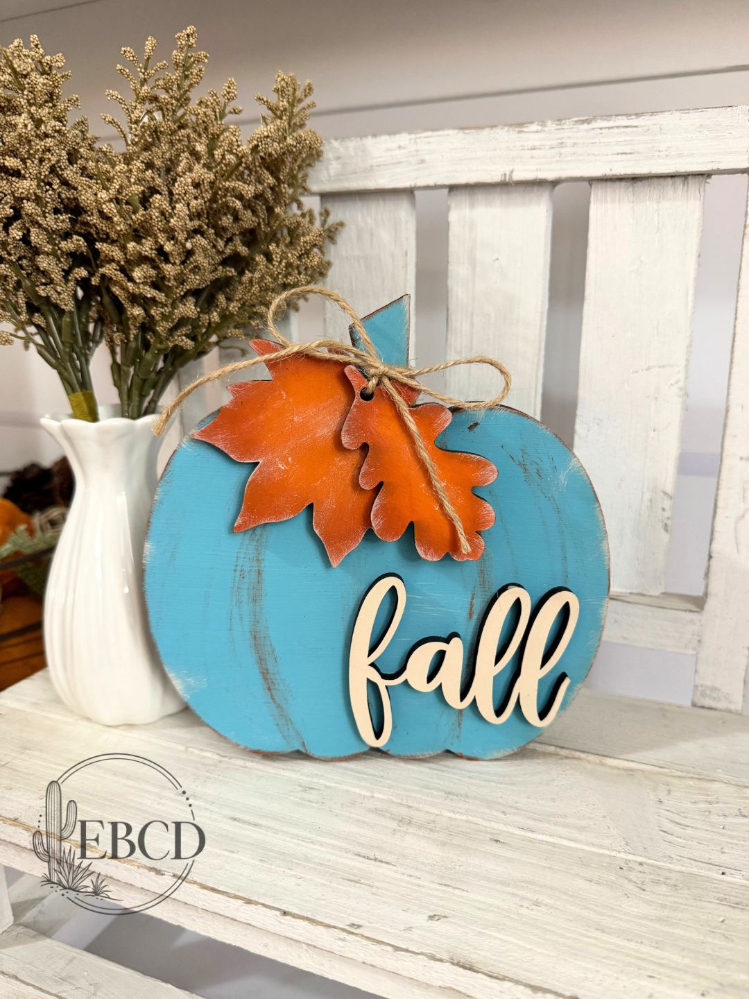 Hand painted chunky fall pumpkin decor in turquoise with orange leaves, natural wood lettering and jute accent.
